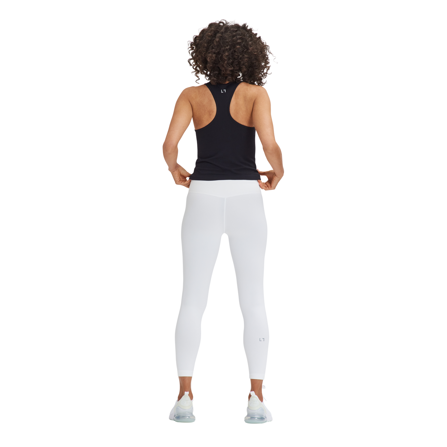 A woman wearing white pants and a black Kulture Noho Seamless Built-In Bra Tank Top.