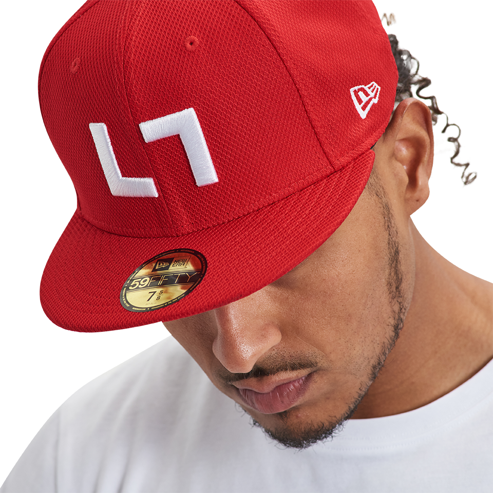 A man wearing a Kulture Authentic Kollection 59FIFTY Fitted hat with white letters on it.