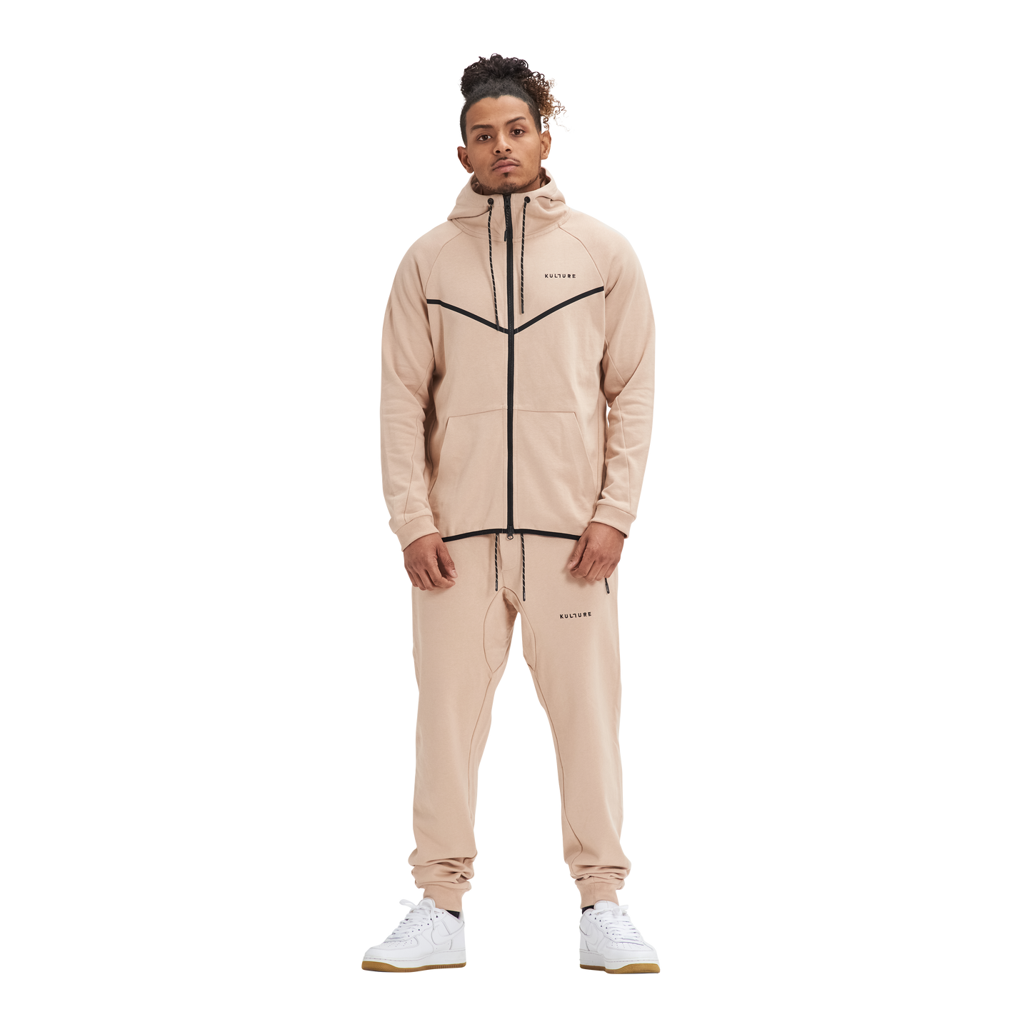 A man in Kulture's ATL Sand Full-Zip Hoodie & Joggers stands in front of a white background.