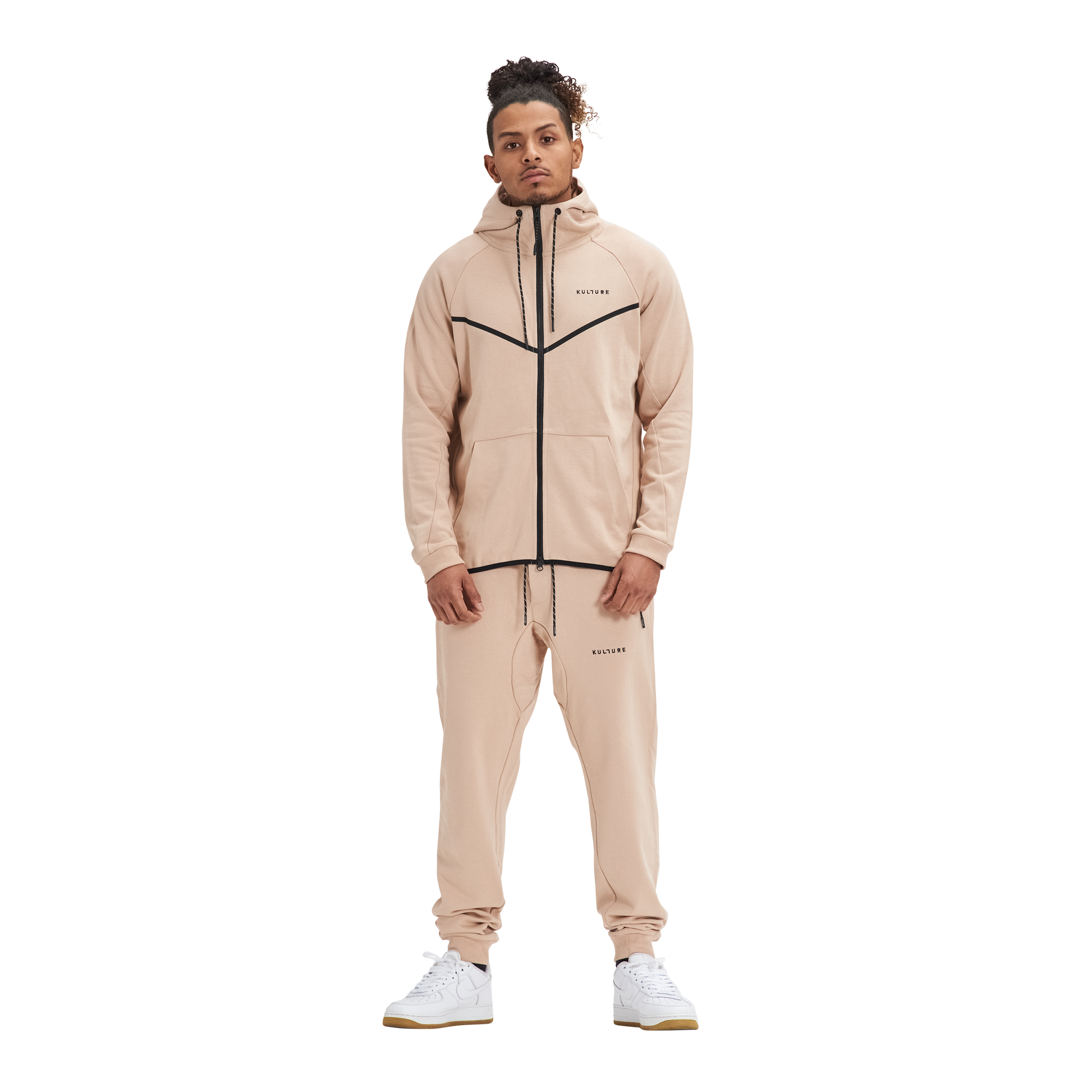 A man in Kulture's ATL Sand Full-Zip Hoodie & Joggers stands in front of a white background.