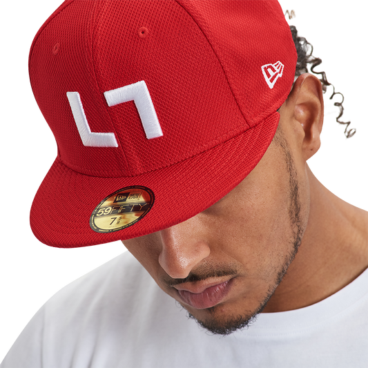 A man wearing a Kulture Authentic Kollection 59FIFTY Fitted hat with white letters on it.