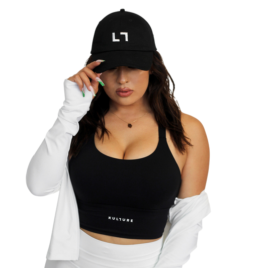 A woman wearing a PHX Kulture Dad Hat and white shorts.
